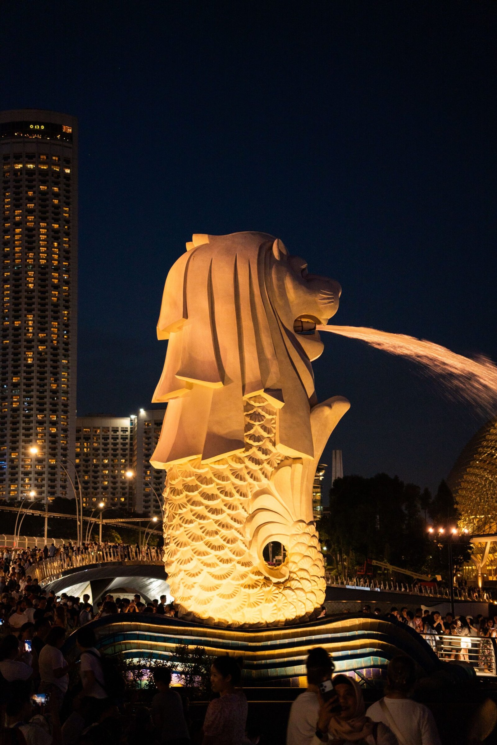 Vibrant night scene of the iconic Merlion statue in Singapore with cityscape.