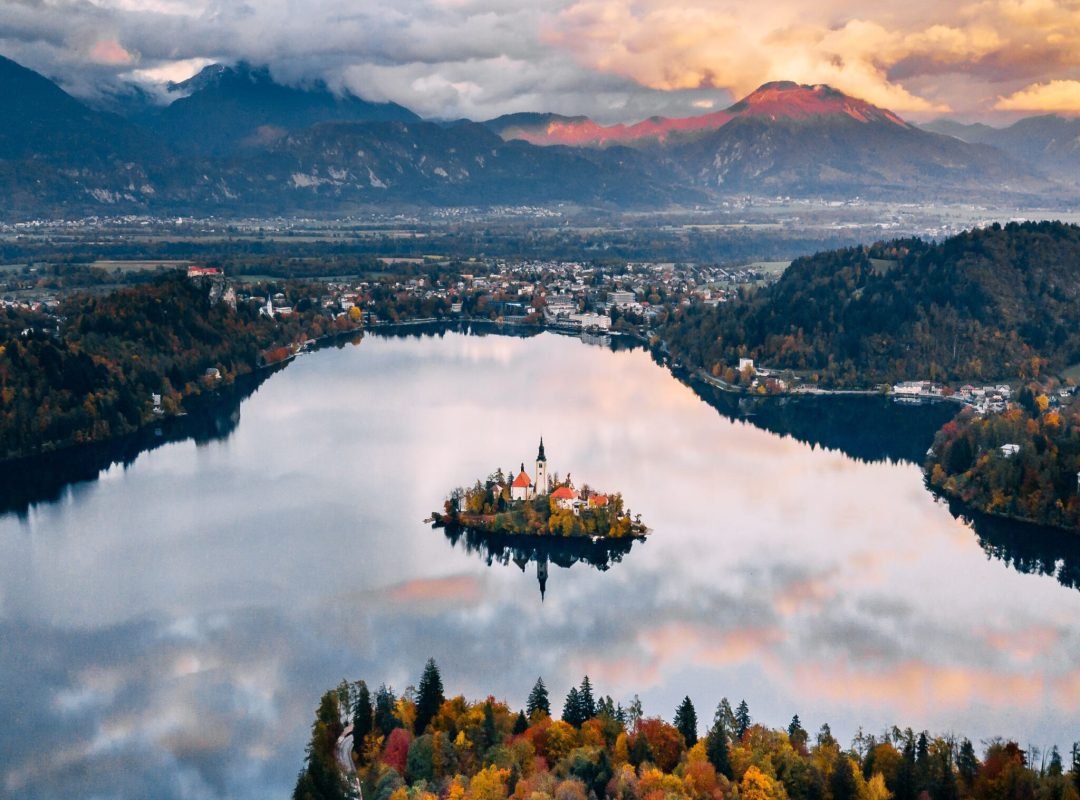 A breathtaking aerial view of Slovenia's Lake Bled surrounded by autumn foliage and mountains.