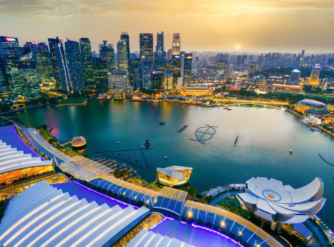 Stunning aerial shot of Singapore's cityscape during sunset with vibrant lights and architecture.
