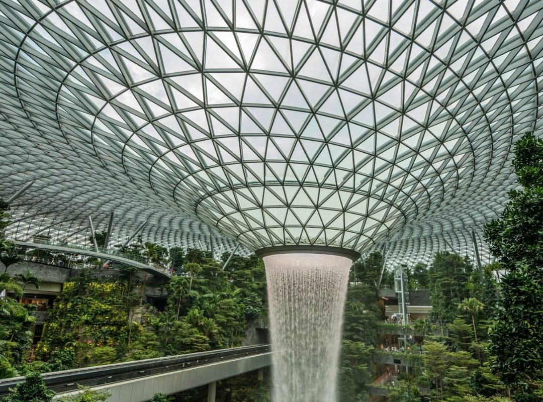 Stunning indoor waterfall surrounded by lush greenery and modern architecture at Singapore's Jewel Changi Airport.