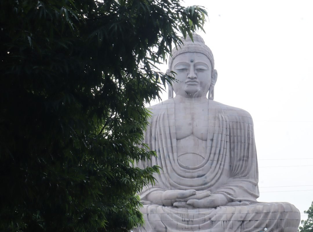 Majestic Great Buddha statue surrounded by green foliage in Bodh Gaya, India.